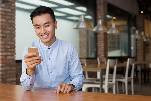 smiling-asian-man-using-smartphone-cafe-table-6
